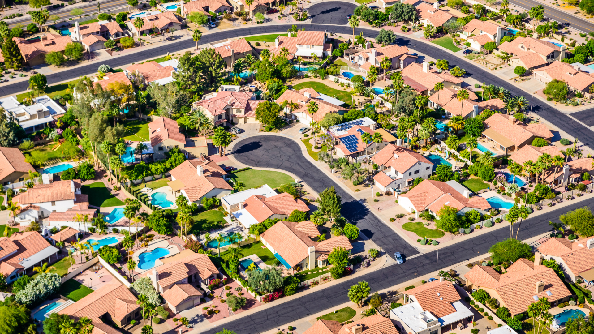 Aerial view of a Scottsdale neighborhood with red-tile roofs, pools, and green yards